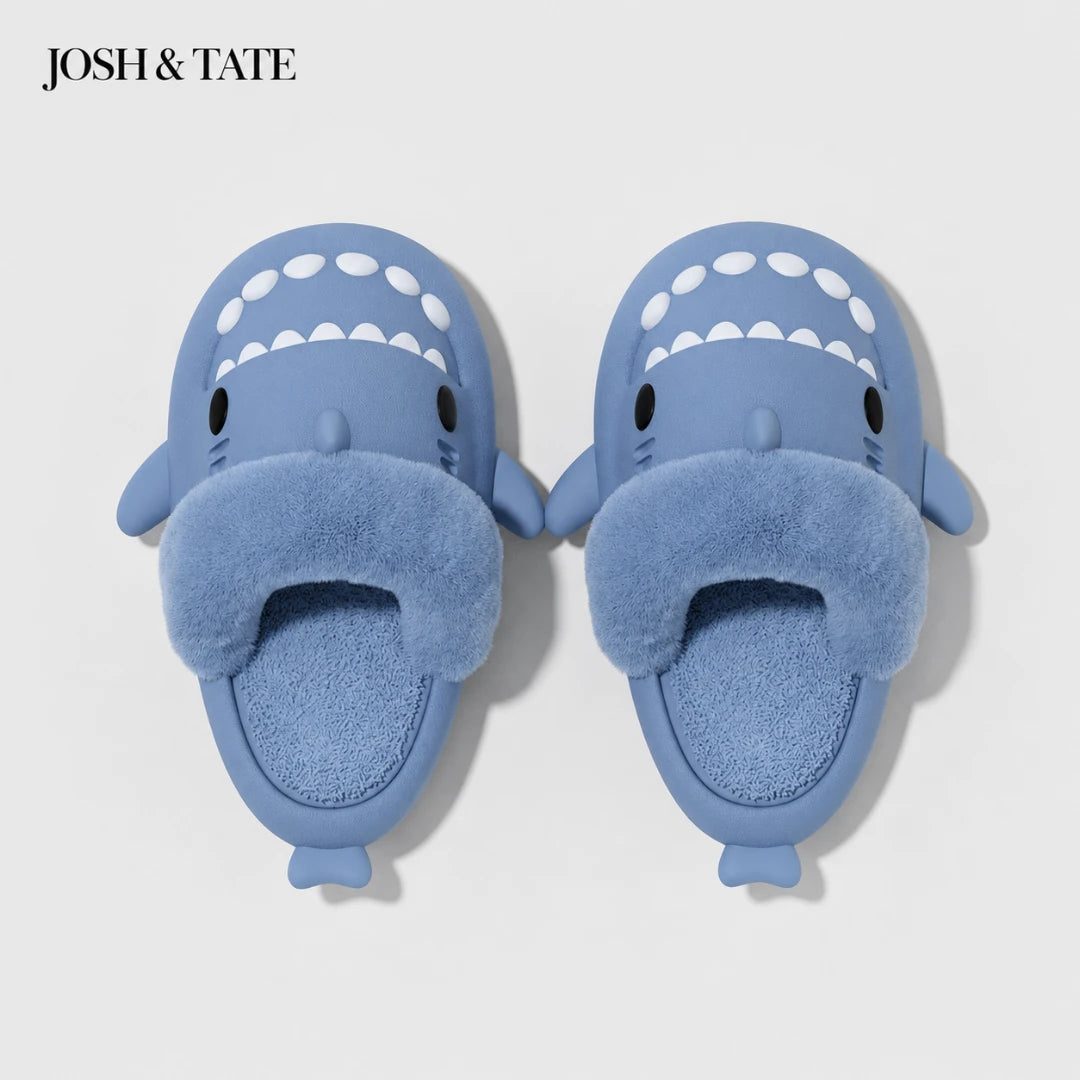 Josh & Tate - SharkStep™ Plush Slip-On Slipper - Blue shark-shaped slippers with a white interior on a light gray background, branded 'JOSH & TATE'.