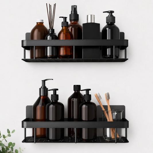 Josh & Tate - ShelfLoft™ Adhesive Shower Shelf - Two black metal wall-mounted bathroom shelves holding assorted toiletry bottles, a reed diffuser, a toothbrush holder with wooden toothbrushes, and a small plant sprig at the lower left, shown against a light gray wall.