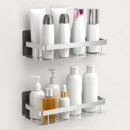 Josh & Tate - ShelfLoft™ Adhesive Shower Shelf - Two wall-mounted chrome bathroom shelves holding assorted toiletries, including white bottles, tubes, and a small amber bottle, against a plain light wall.