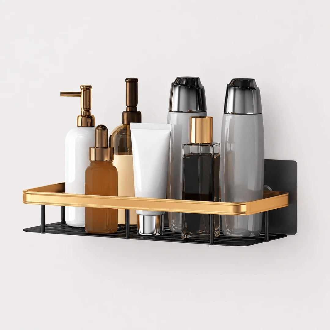 Josh & Tate - ShelfLoft™ Adhesive Shower Shelf - A wall-mounted bathroom organizer shelf with a gold metal tray and black wire base, holding assorted toiletry bottles and containers against a light gray wall.