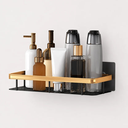 Josh & Tate - ShelfLoft™ Adhesive Shower Shelf - A wall-mounted bathroom organizer shelf with a gold metal tray and black wire base, holding assorted toiletry bottles and containers against a light gray wall.