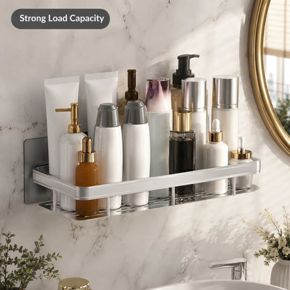 Josh & Tate - ShelfLoft™ Adhesive Shower Shelf - A wall-mounted bathroom organizer shelf holding assorted toiletry bottles and containers, shown against a white marble wall with a round mirror edge visible. A dark badge in the top left reads 'Strong Load Capacity'.