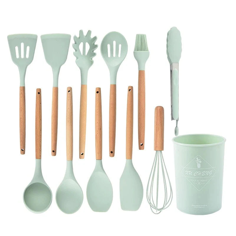 Set of kitchen utensils with wooden handles and a green cup on a white background