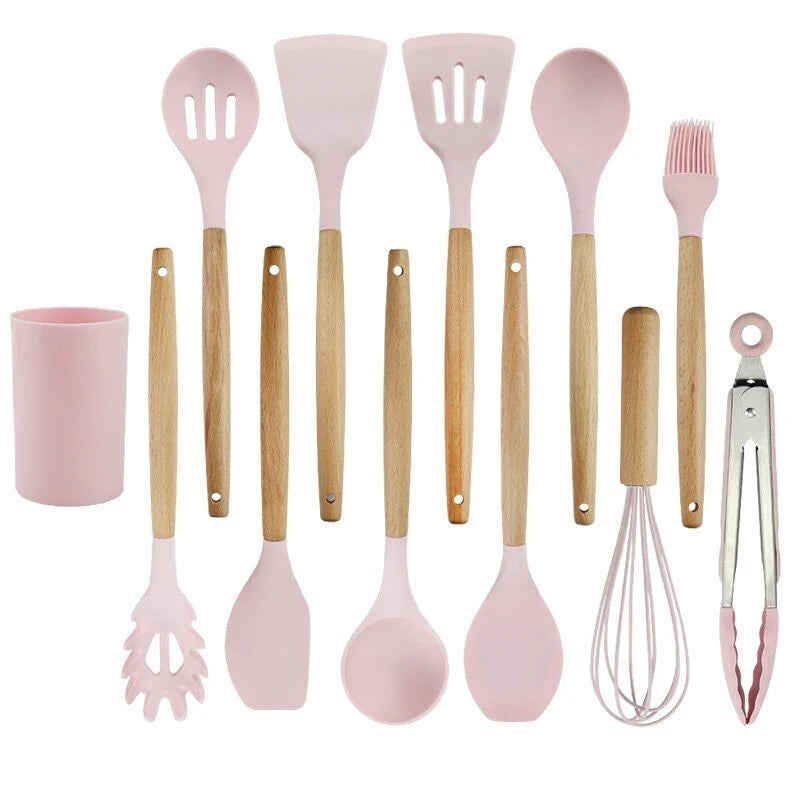 Set of pink kitchen utensils with wooden handles on a white background