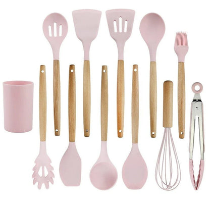 Set of pink kitchen utensils with wooden handles on a white background