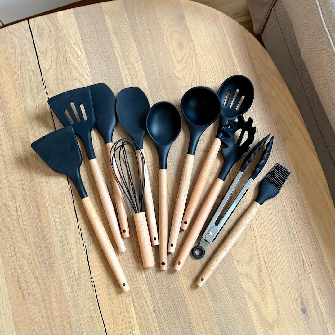 Set of black and beige kitchen utensils on a wooden surface