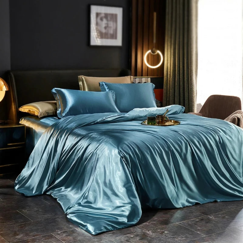 Blue satin bedding set on a bed in a bedroom with dark walls and a lamp.