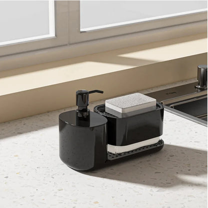 Black kitchen sink caddy with soap dispenser and sponge holder on a countertop.