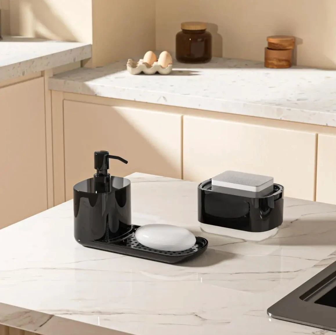 Black kitchen sink caddy with soap dish and container on a marble countertop.