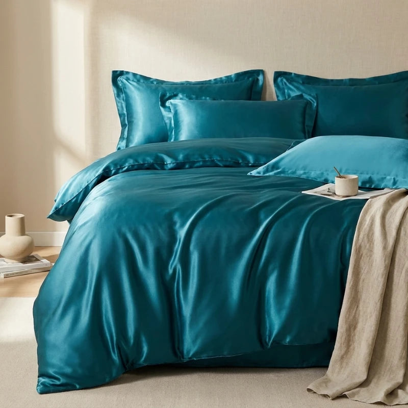 Teal satin bedding set on a bed with a beige wall and light-colored floor.