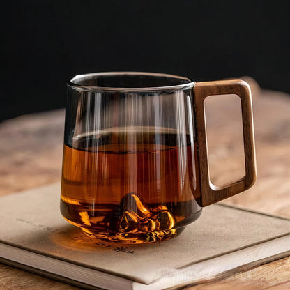 Clear glass mug with wooden handle filled with a warm beverage on an open book