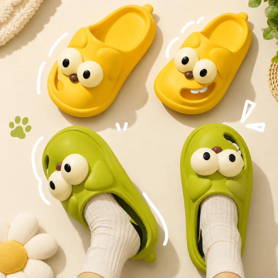 Josh & Tate - SnaggleToe™ Slides - Four cartoon-style slip-on slippers arranged on a light beige surface, with two yellow slippers at the top and two green slippers at the bottom. The slippers have large round eyes and small smiling faces.