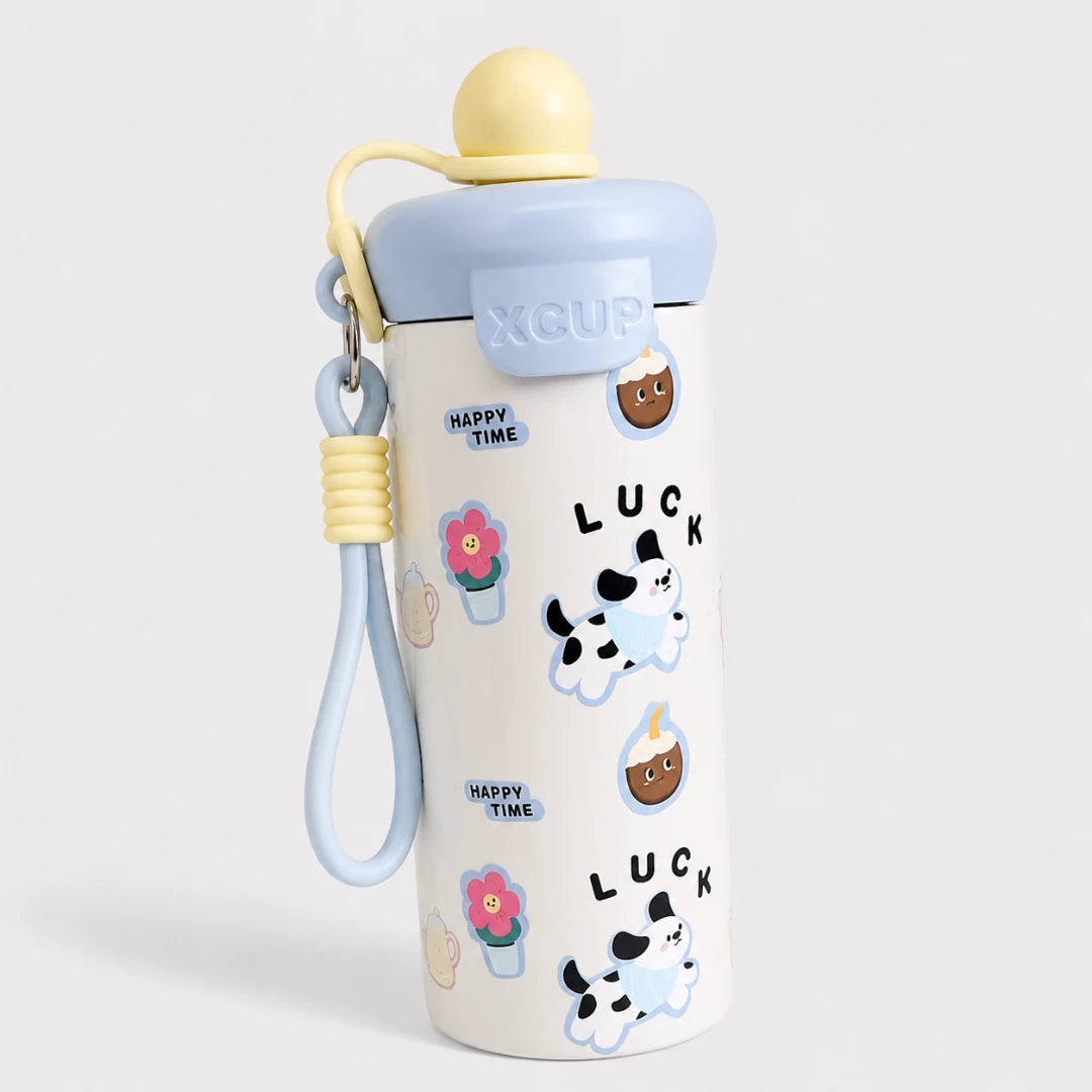 Josh & Tate - SnugPop™ Cute Insulated Tumbler - A Yggdrasil brand insulated water bottle with a white body decorated with cute cartoon cow, flower, and 'LUCK' illustrations. It features a light blue lid, a pale yellow cap, and a matching light blue wrist strap with a yellow cord lock.