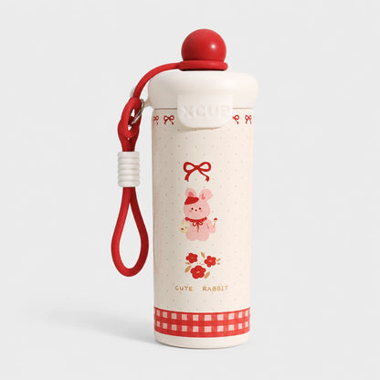 Josh & Tate - SnugPop™ Cute Insulated Tumbler - A cream-colored insulated water bottle with a red lid, red carrying strap, and cute pink rabbit illustration on the front, set against a light gray background.
