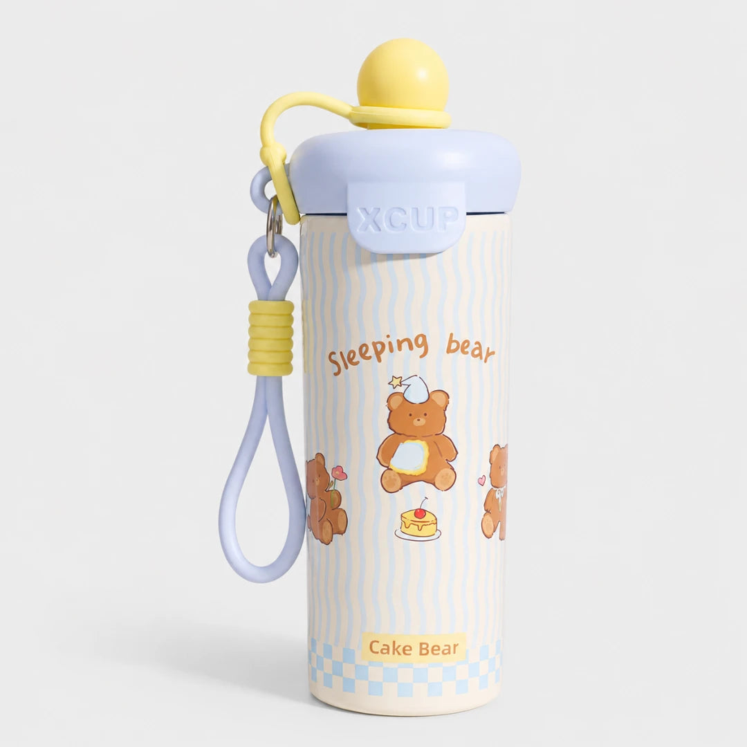 Josh & Tate - SnugPop™ Cute Insulated Tumbler - A cute stainless steel water bottle with a lid, featuring a cartoon teddy bear design and the text 'Sleeping bear' and 'Cake Bear'. It has a light blue lid, a yellow cap, and a matching light blue and yellow wrist strap, set against a light gray background.