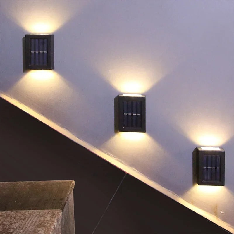 Three square wall lights on a wall with a dark floor and light-colored wall.
