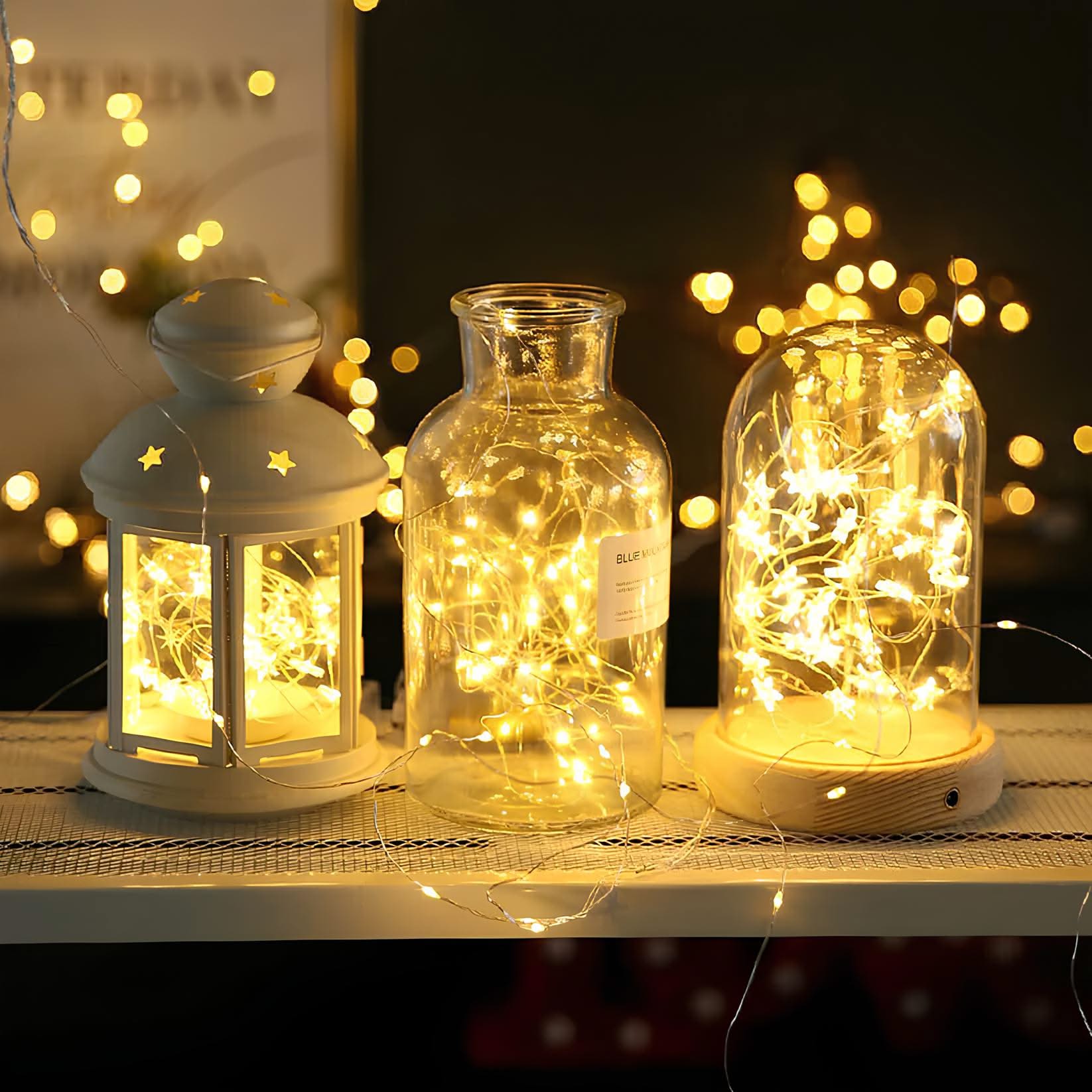Decorative lanterns and jars with string lights on a table with a blurred background of lights.