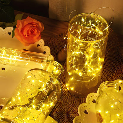 Decorative glass jars with string lights on a textured surface.