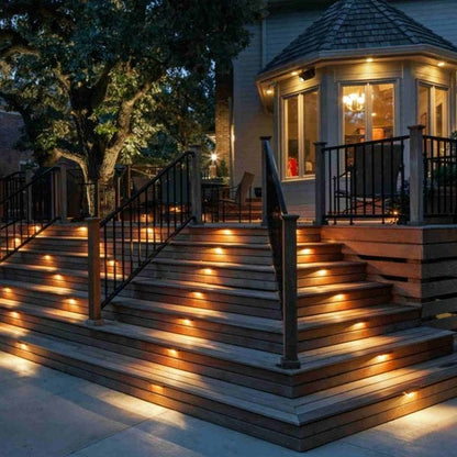 Wooden staircase with embedded lights leading to a house at night.