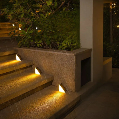 Staircase with embedded lights at night, surrounded by greenery.