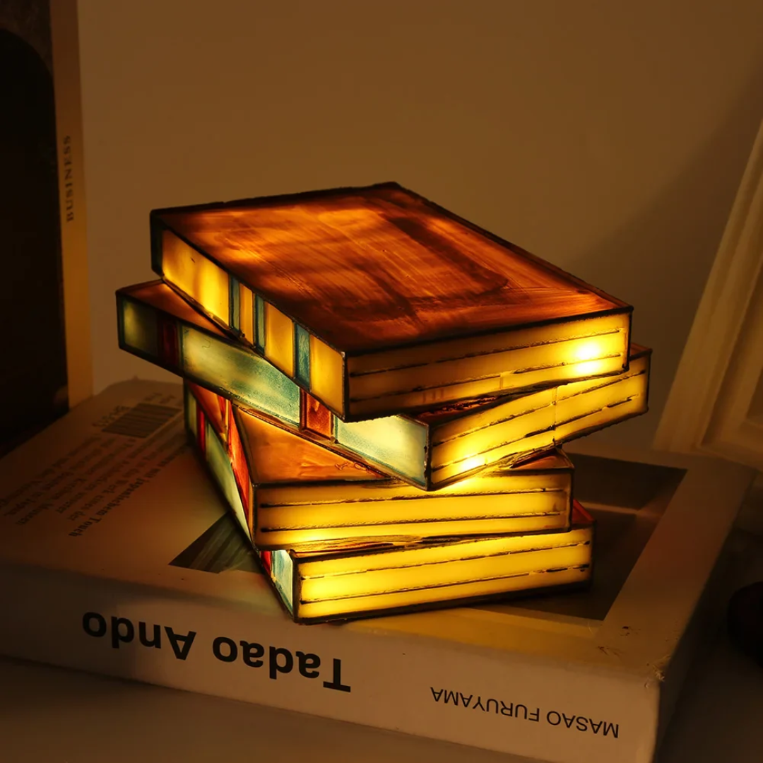 Stack of books shaped like a lamp with warm glow on top of a book titled 'Tadpo Ando' by Masao Furuyama.