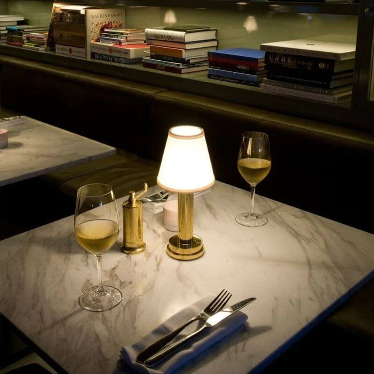 Table setting with wine glasses, lamp, and cutlery on a marble surface.