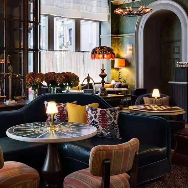 Cozy interior of a restaurant with dark leather couches, patterned chairs, and decorative lighting.