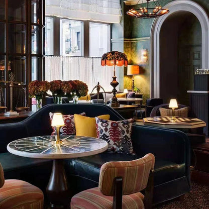 Cozy interior of a restaurant with dark leather couches, patterned chairs, and decorative lighting.