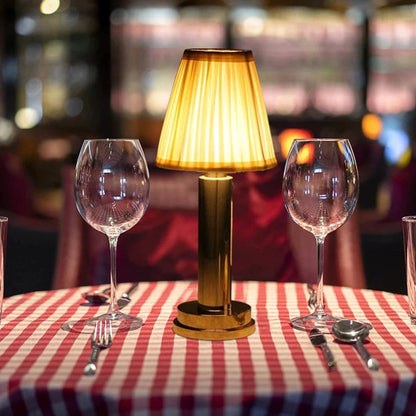 Table setting with wine glasses, lamp, and cutlery on a checkered tablecloth.