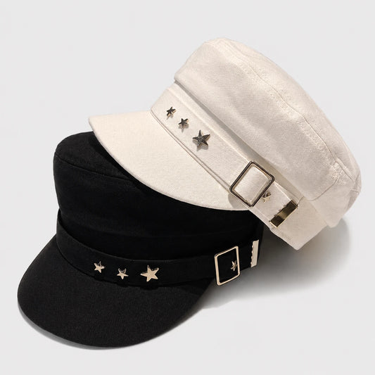 Josh & Tate - StarHat™ Retro Beret - Two structured newsboy-style caps with curved brims and decorative star embellishments on the headband, shown on a light gray studio background. One cap is off-white/cream and the other is black, both with gold-tone buckle and star details.