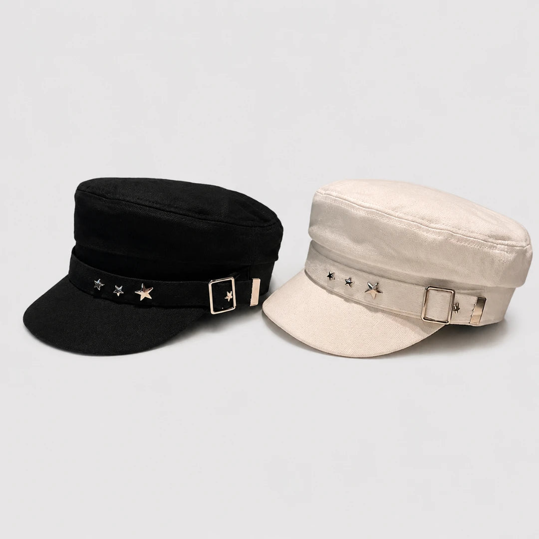 Josh & Tate - StarHat™ Retro Beret - Two military-style newsboy caps shown on a light gray background, one in black and one in cream. Both feature a structured crown, a curved brim, a matching fabric band with star embellishments, and a square buckle closure.