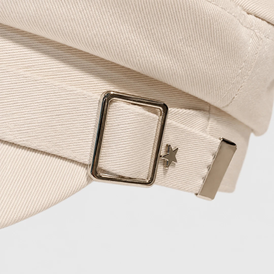 Josh & Tate - StarHat™ Retro Beret - Close-up of a cream-colored fabric belt with a polished silver-tone buckle and a small star-shaped metal accent.