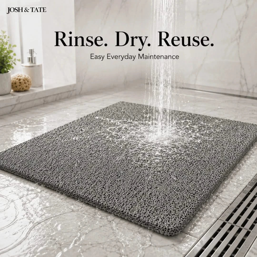 Josh & Tate - StepDry™ Anti-Slip Bath Mat - Gray bath mat on a bathroom floor with water being rinsed over it, featuring 'Josh & Tate' branding.