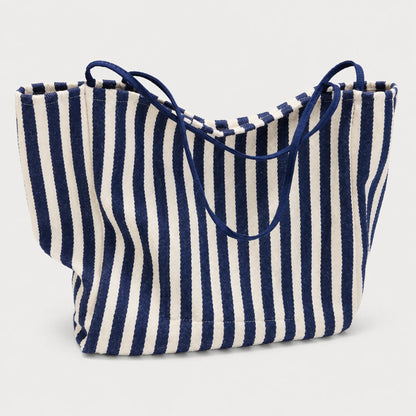 Josh & Tate - StripeCarry™ Oversized Tote Bag - A woven tote bag with vertical navy blue and off-white stripes, featuring dark navy blue shoulder straps, shown against a light gray background.