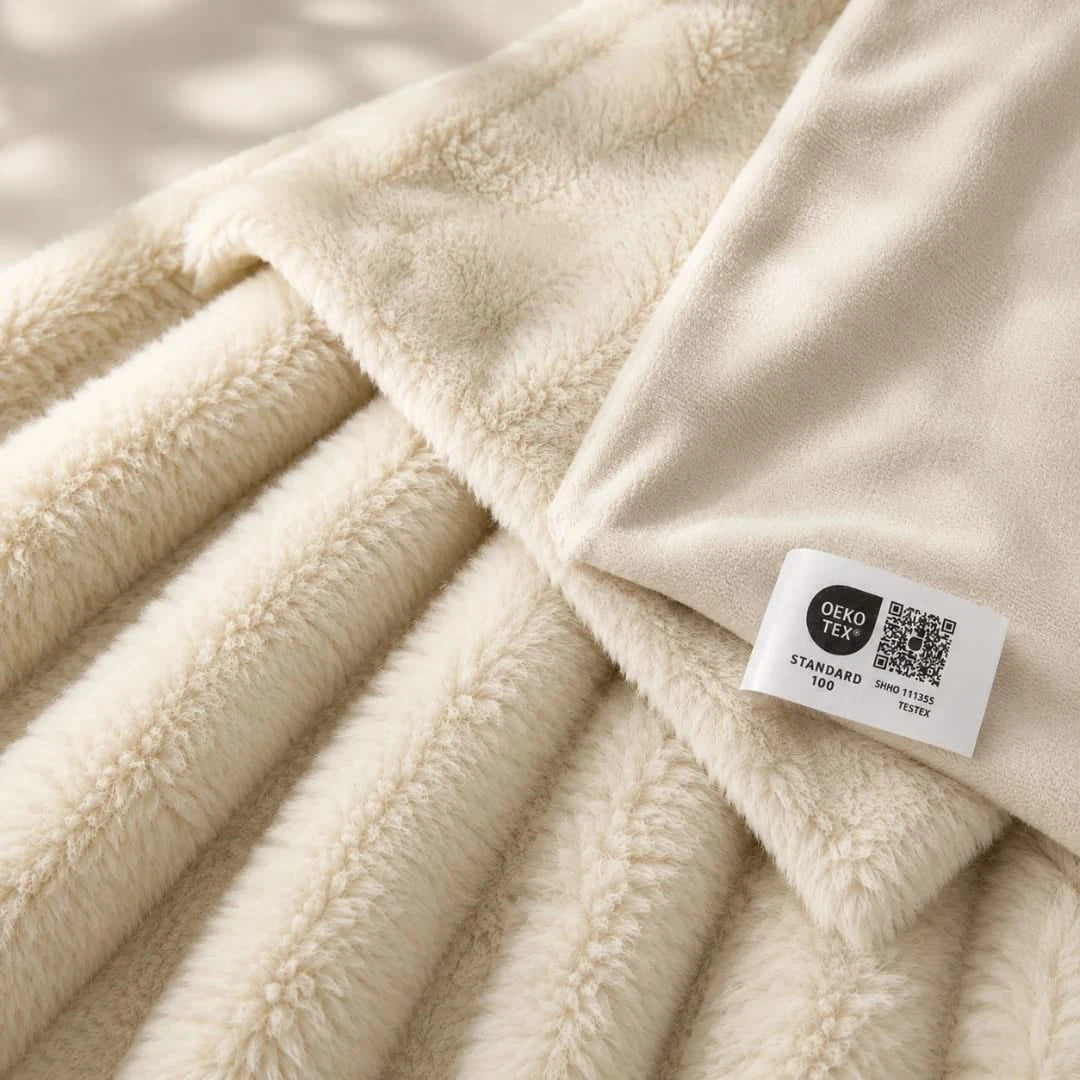 Beige fleece blanket with an OKO-TEX label on a neutral background