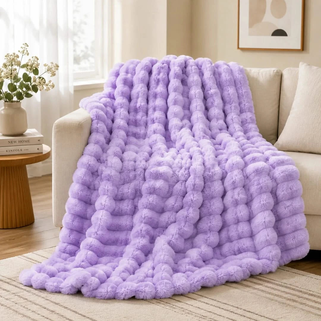 Purple textured blanket draped over a couch in a living room setting.