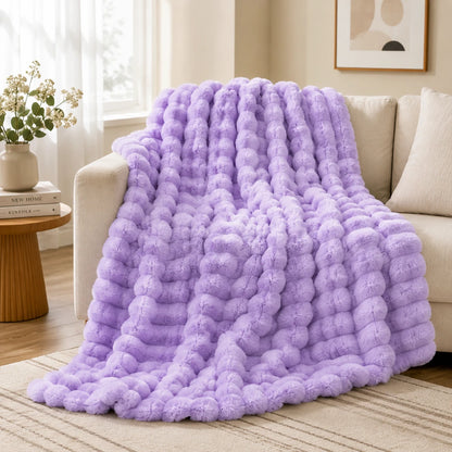 Purple textured blanket draped over a couch in a living room setting.