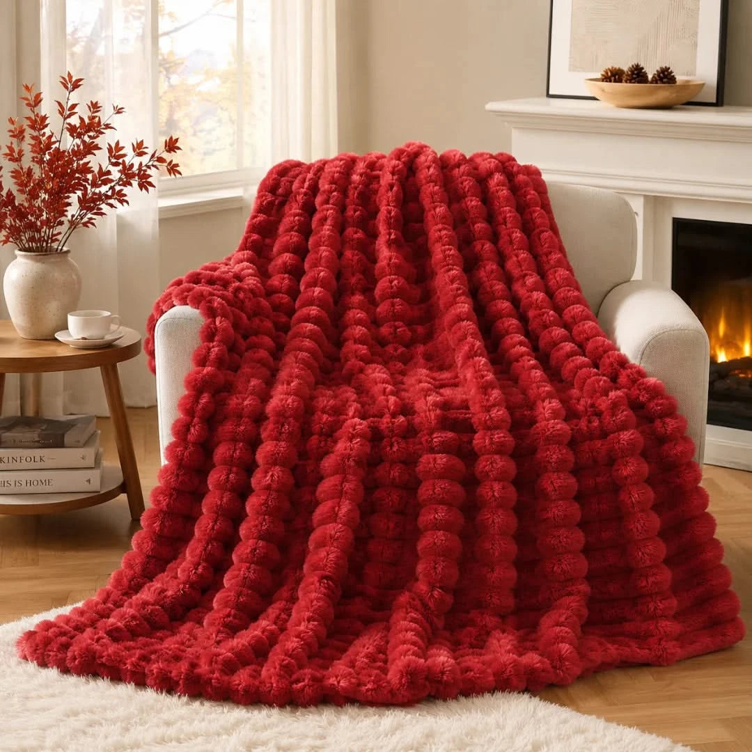 Red textured blanket draped over a chair in a cozy living room with a fireplace.