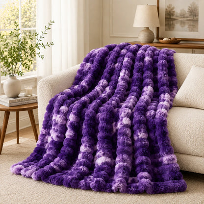 Purple textured blanket draped over a beige sofa in a living room.