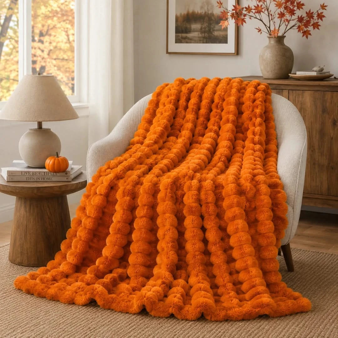 Orange textured blanket draped over a chair in a cozy living room.