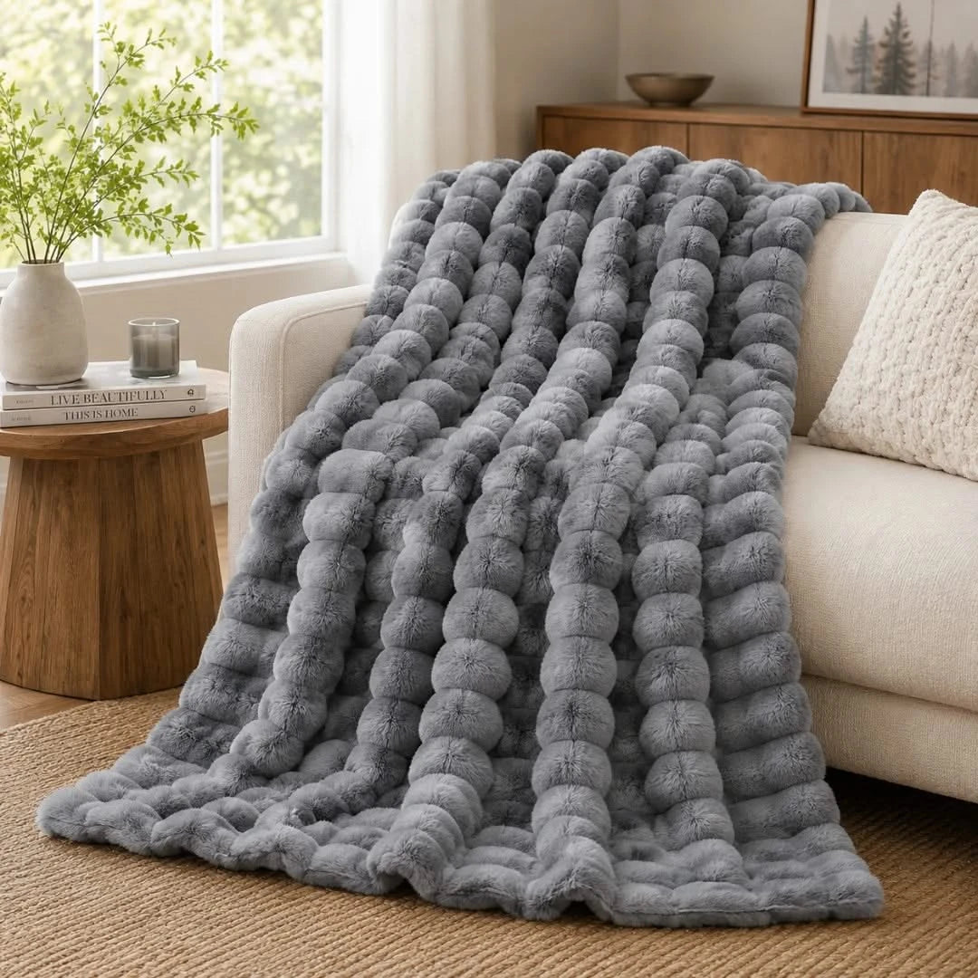 Gray textured blanket draped over a sofa in a cozy living room.