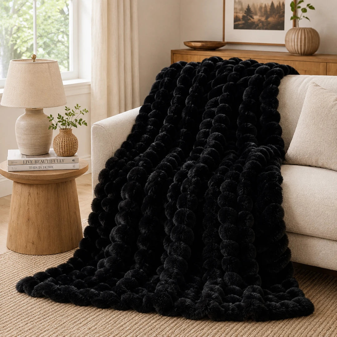 Black textured blanket draped over a beige sofa in a living room setting.