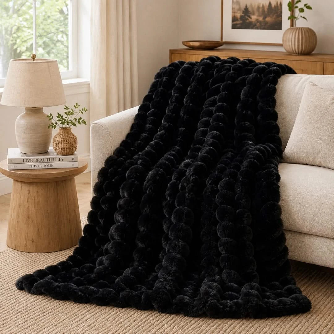 Black textured blanket draped over a beige sofa in a living room setting.