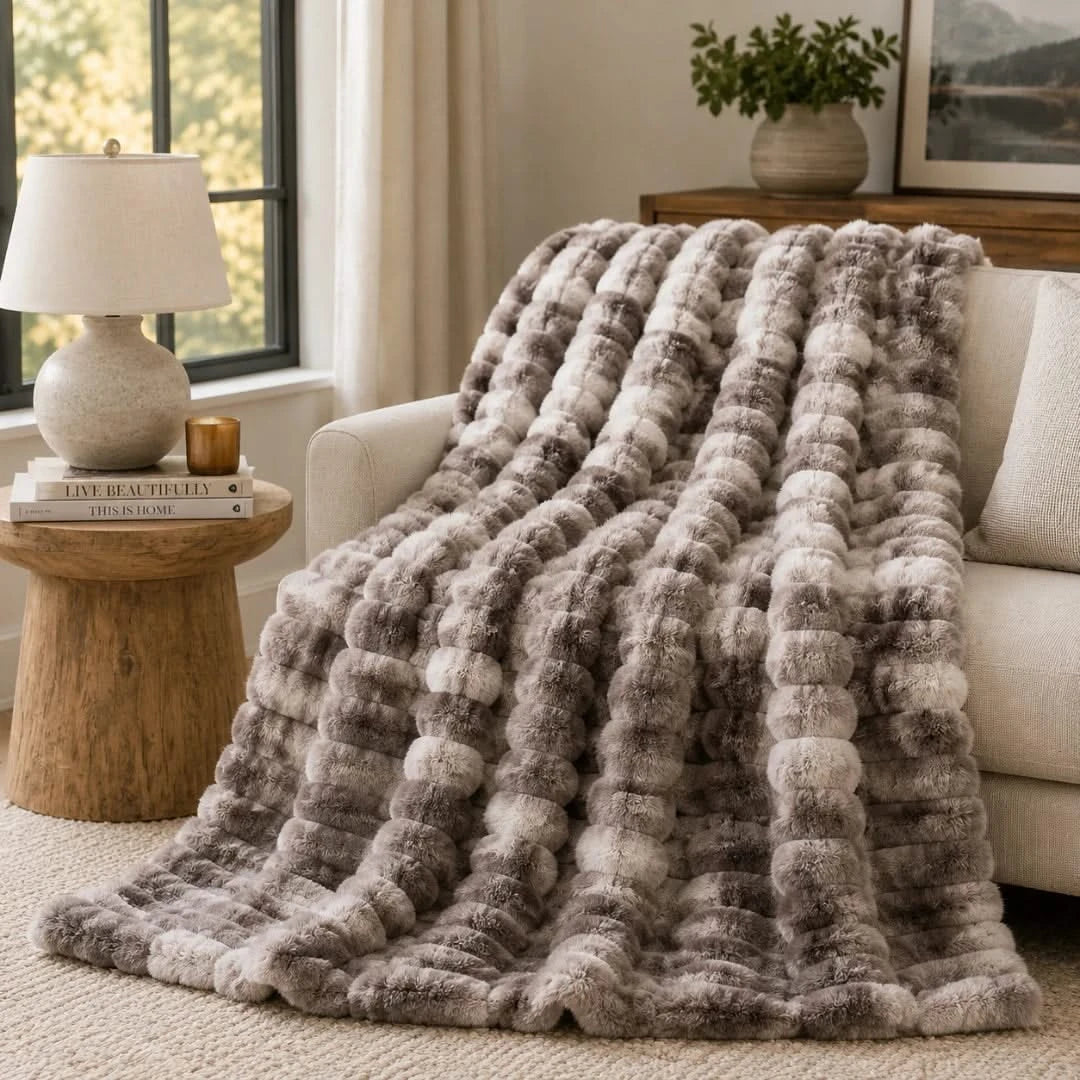 Fluffy gray blanket draped over a sofa in a cozy living room.