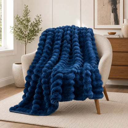 Blue textured blanket draped over a chair in a room with a plant and dresser.