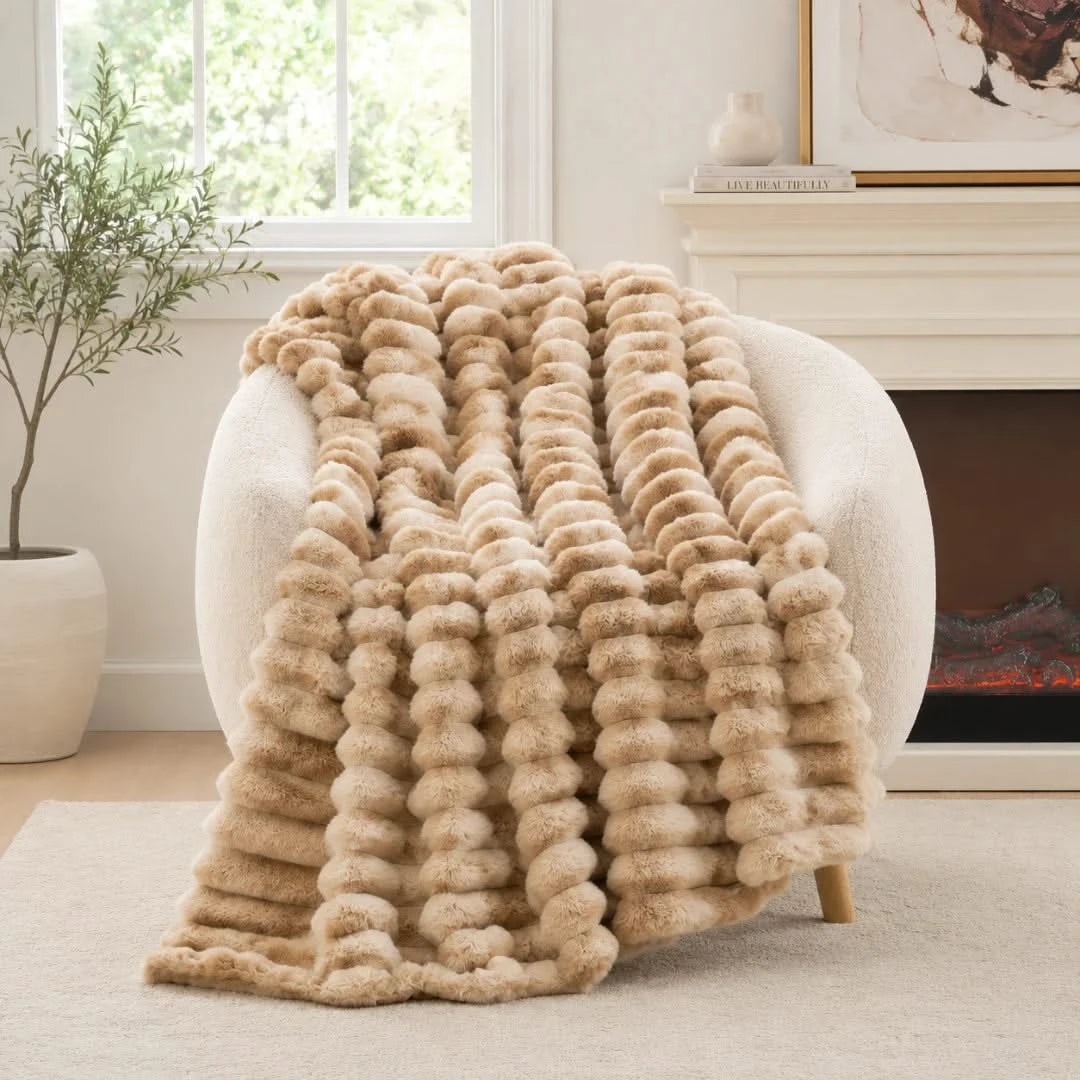 Beige textured blanket draped over a white armchair in a cozy living room.