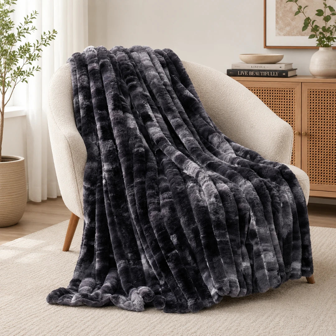 Dark gray textured blanket draped over a white armchair in a cozy living room.