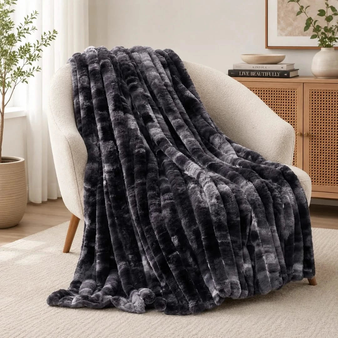 Dark gray textured blanket draped over a white armchair in a cozy living room.