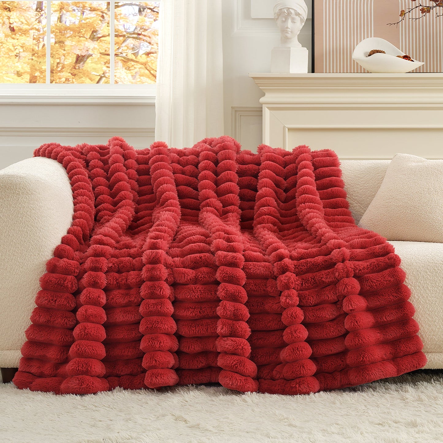 Red textured blanket draped over a white sofa in a living room.