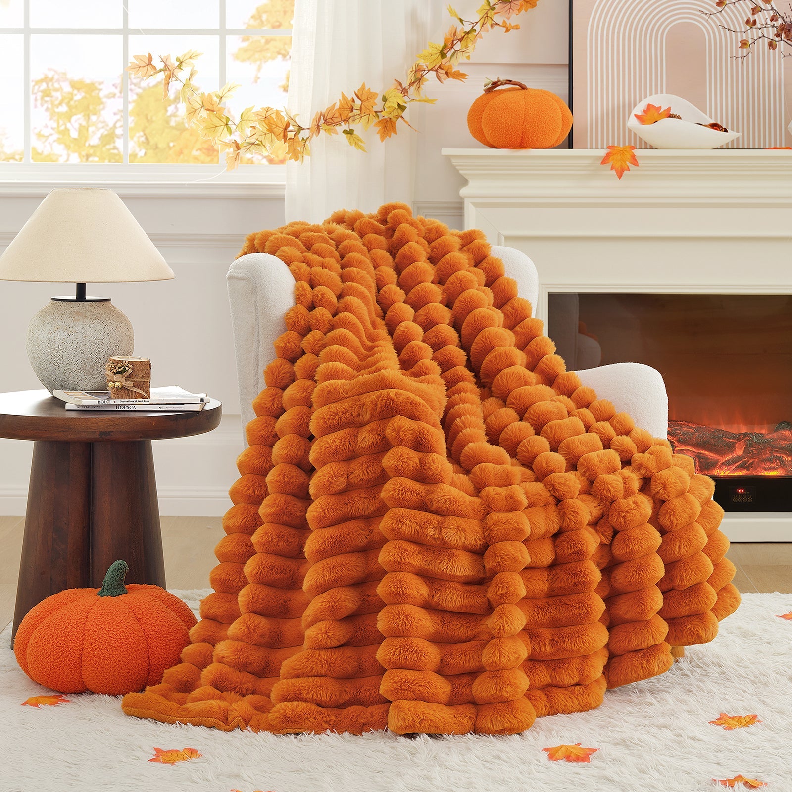 Orange fluffy blanket draped over a chair in a cozy living room with pumpkins and autumn decorations.